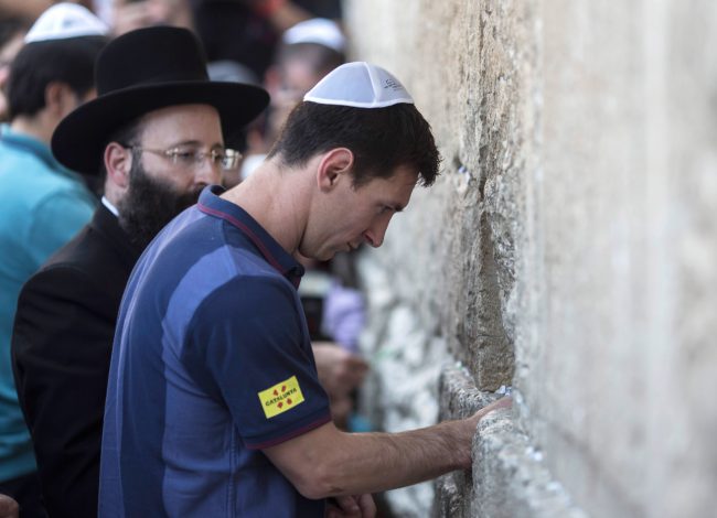 Argentine soccer player Lionel Messi puts a paper with wishes in a crack in the Western Wall on August 4, 2013 in Jerusalem, Israel during a "peace tour" by members of the FC Barcelona squad.


