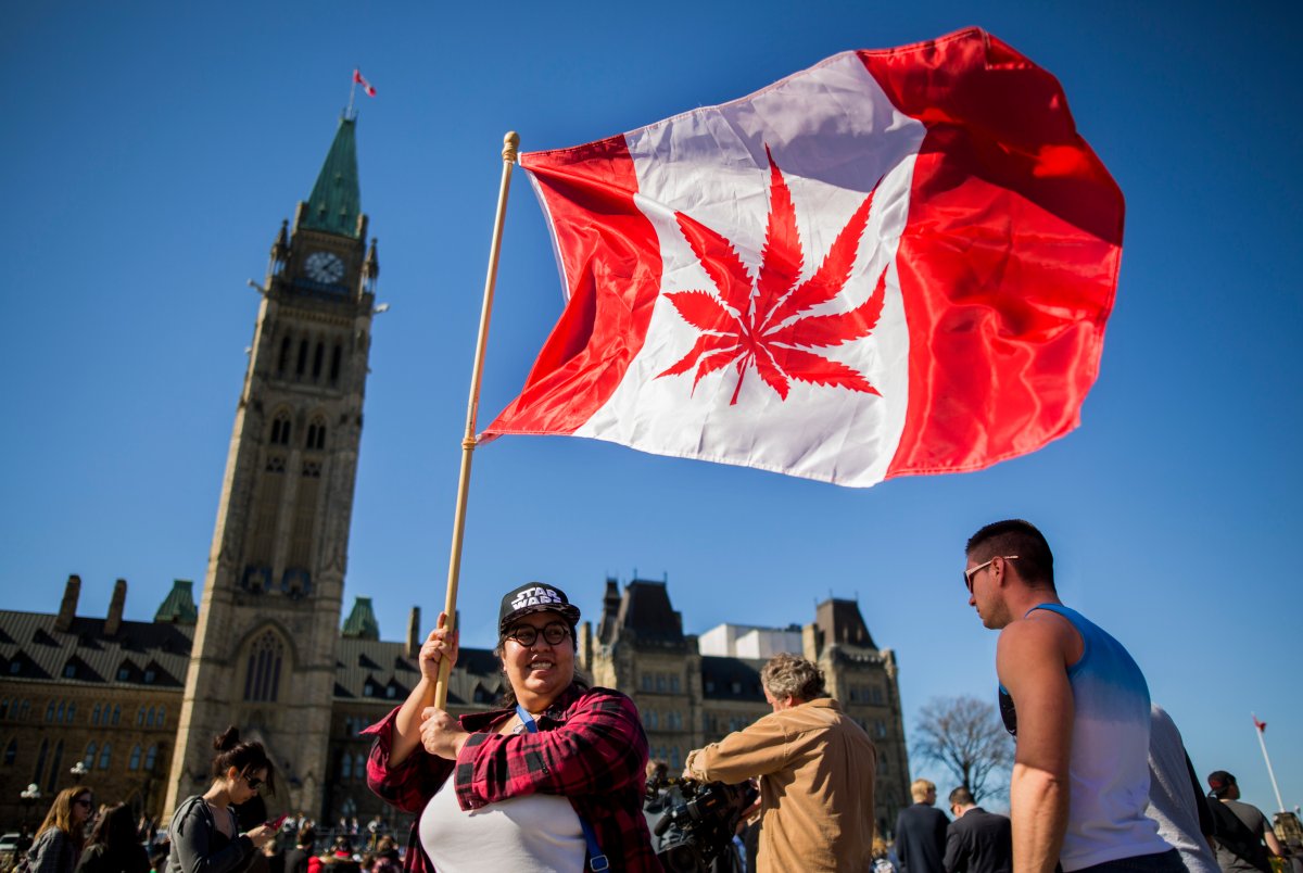 A woman waves a flag with a marijuana leaf on it next to a group gathered to celebrate National Marijuana Day on Parliament Hill in Ottawa, Canada on April 20, 2016. Canada will take steps next year to legalize marijuana, Health Minister Jane Philpott announced. Philpott offered several reasons for ending the ban on pot, including the view that laws in Canada and abroad criminalizing marijuana use have been both overly-harsh and ineffective. / AFP / Chris Roussakis (Photo credit should read CHRIS ROUSSAKIS/AFP/Getty Images).