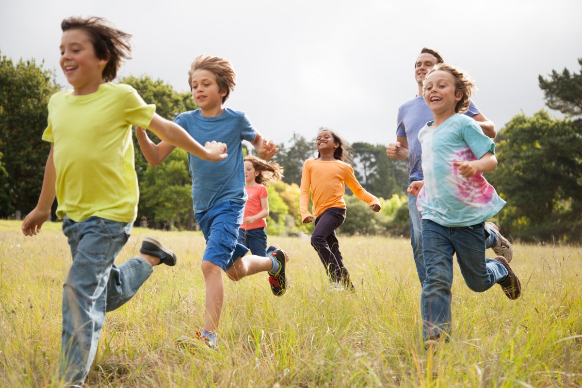 Children, aged 9-10, running together in a park.