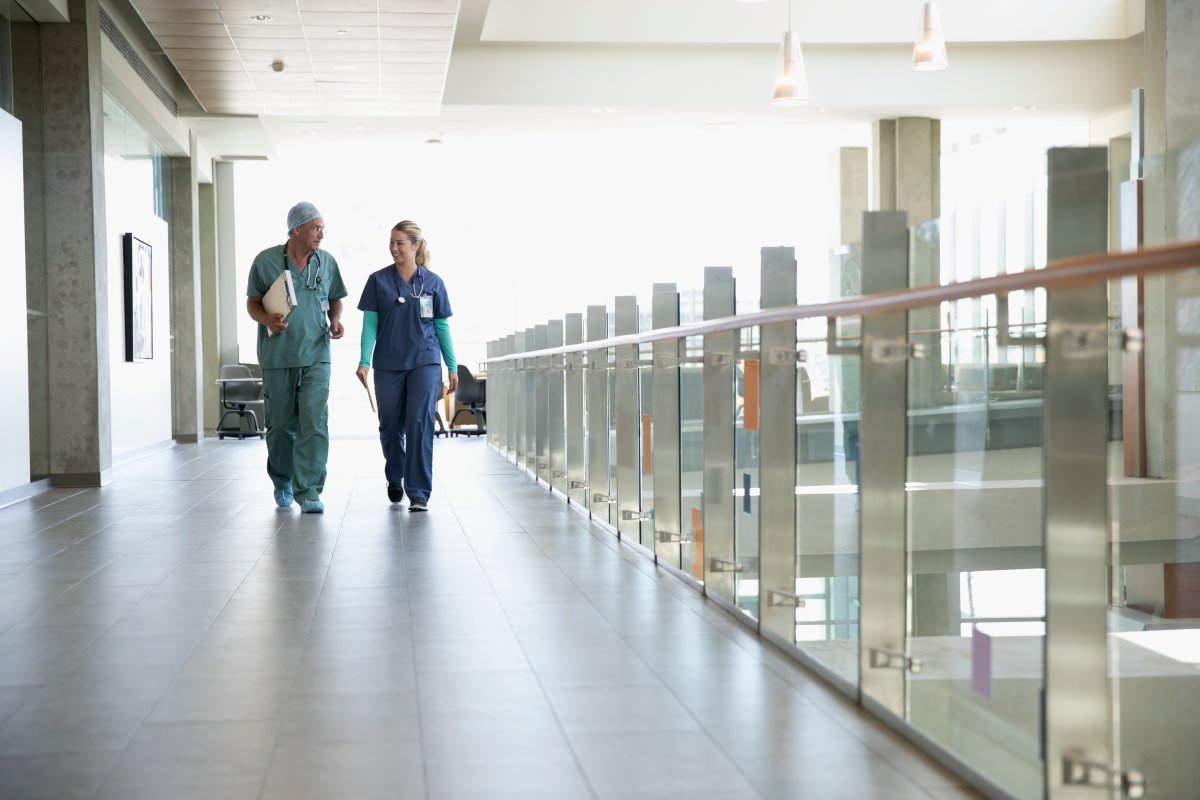 Surgeon and nurse walking and talking in hospital corridor.