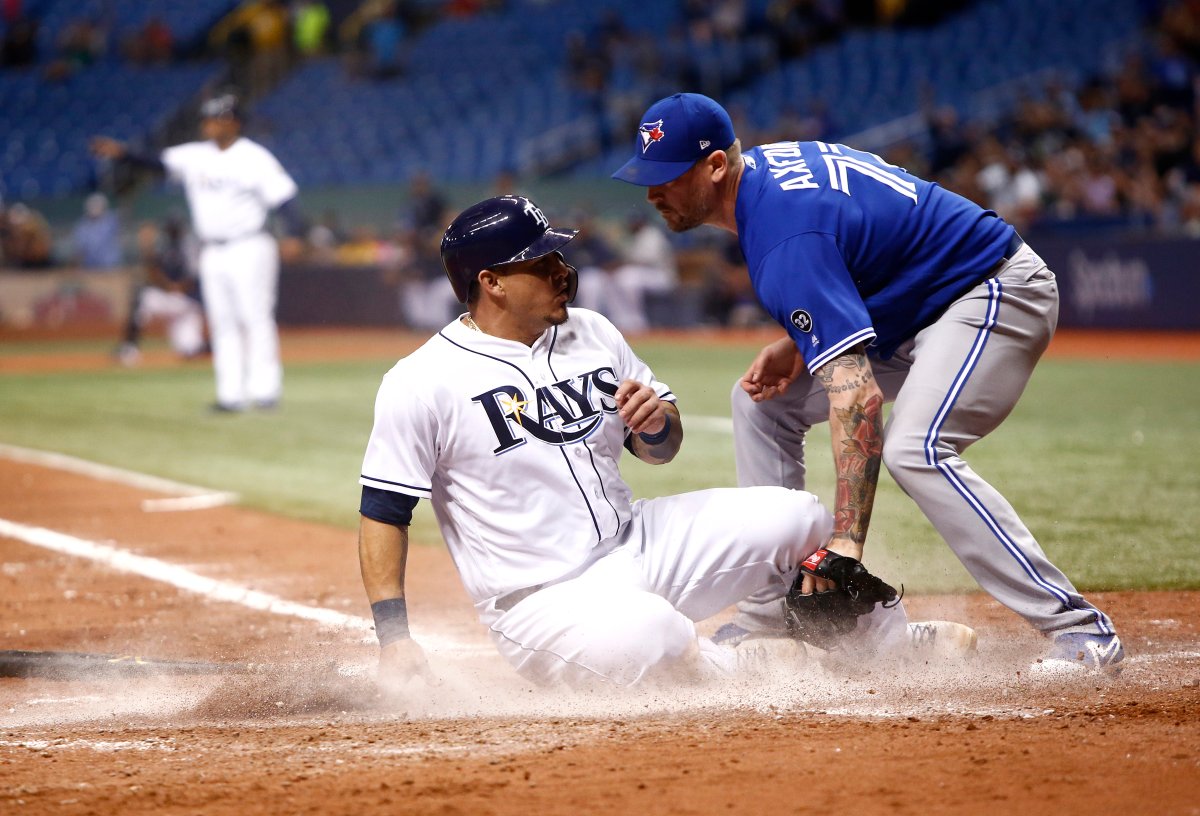 ST. PETERSBURG, FL - JUNE 11:  Wilson Ramos #40 of the Tampa Bay Rays slides home safely ahead of pitcher John Axford #77 of the Toronto Blue Jays to score off of a throwing error by Axford during the seventh inning of a game on June 11, 2018 at Tropicana Field in St. Petersburg, Florida.  