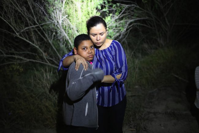 A U.S. Border Patrol spotlight shines on a terrified mother and son from Honduras as they are found in the dark near the U.S.-Mexico border in McAllen, Texas, June 12, 2018