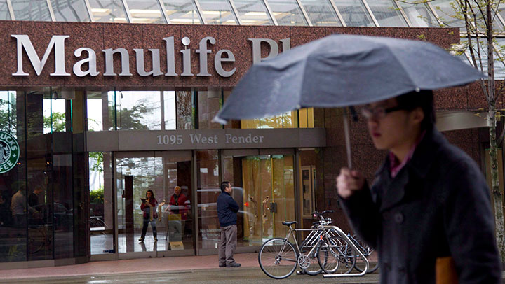 A pedestrian walks past the Manulife building in downtown Vancouver, B.C., Thursday, May 3, 2012. 