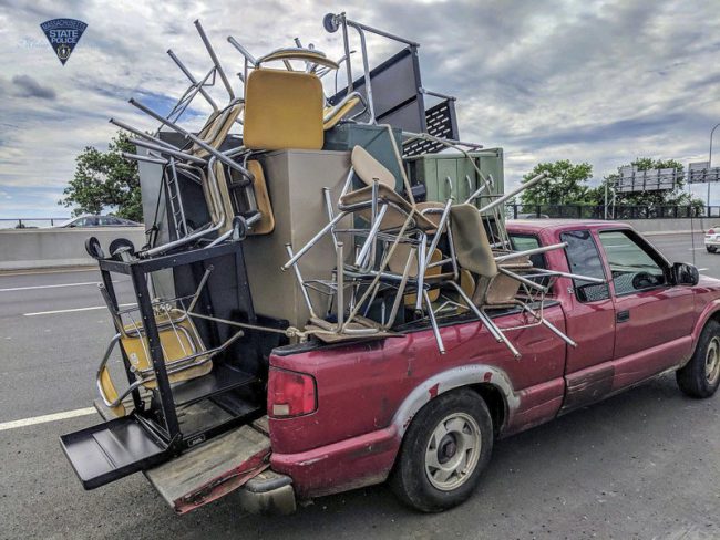 This June 20, 2018 photo released by Massachusetts State Police shows an overloaded truck pulled over for uncovered cargo on Interstate 91 in Springfield, Mass.