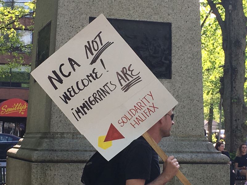 A protester holds up a sign at Victoria Park in Halifax ahead of a planned rally by the National Citizens Alliance on Friday, June 1, 2018.