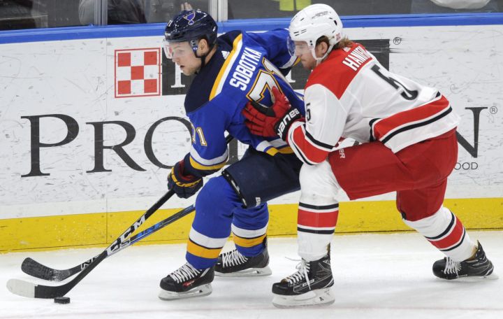 St. Louis Blues’ Vladimir Sobotka (71), of the Czech Republic, reaches for the puck with Carolina Hurricanes’ Noah Hanifin (5) during the second period of an NHL hockey game Saturday, Dec. 30, 2017, in St. Louis.