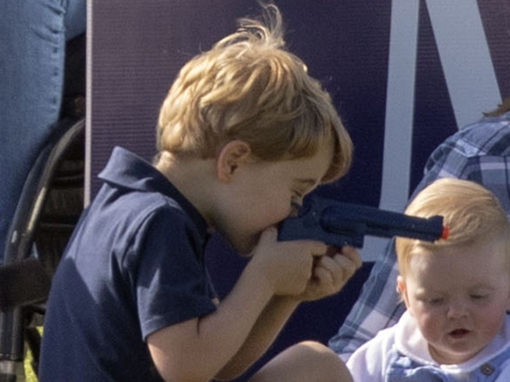 Prince George plays with a toy gun at the Maserati Royal Charity Polo Trophy.
