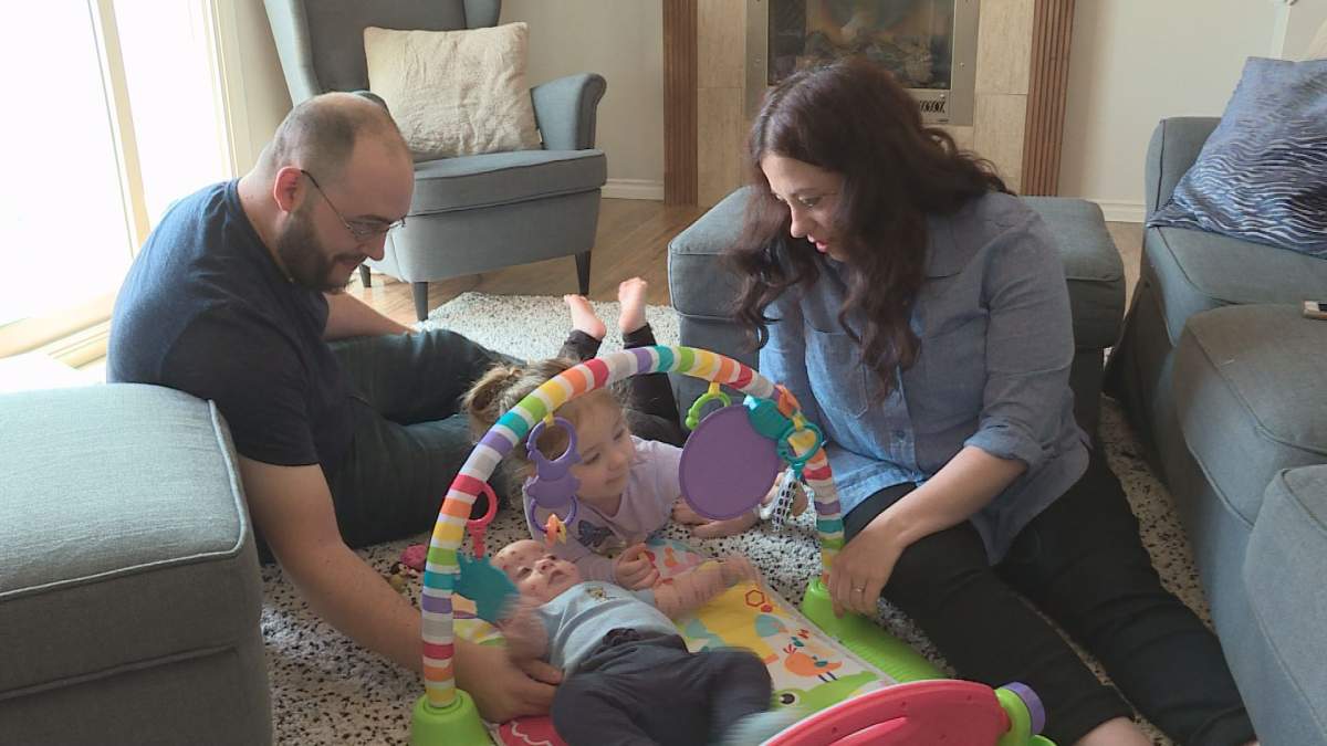 Jarrod, daughter Zoë and Meagan play with Dominic in their living room.