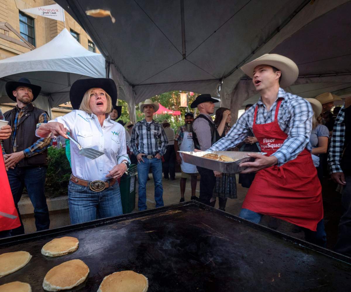 Alberta Premier Rachel Notley flips pancakes as she attends her annual Stampede breakfast in Calgary on Monday, July 9, 2018. THE CANADIAN PRESS/Jeff McIntosh