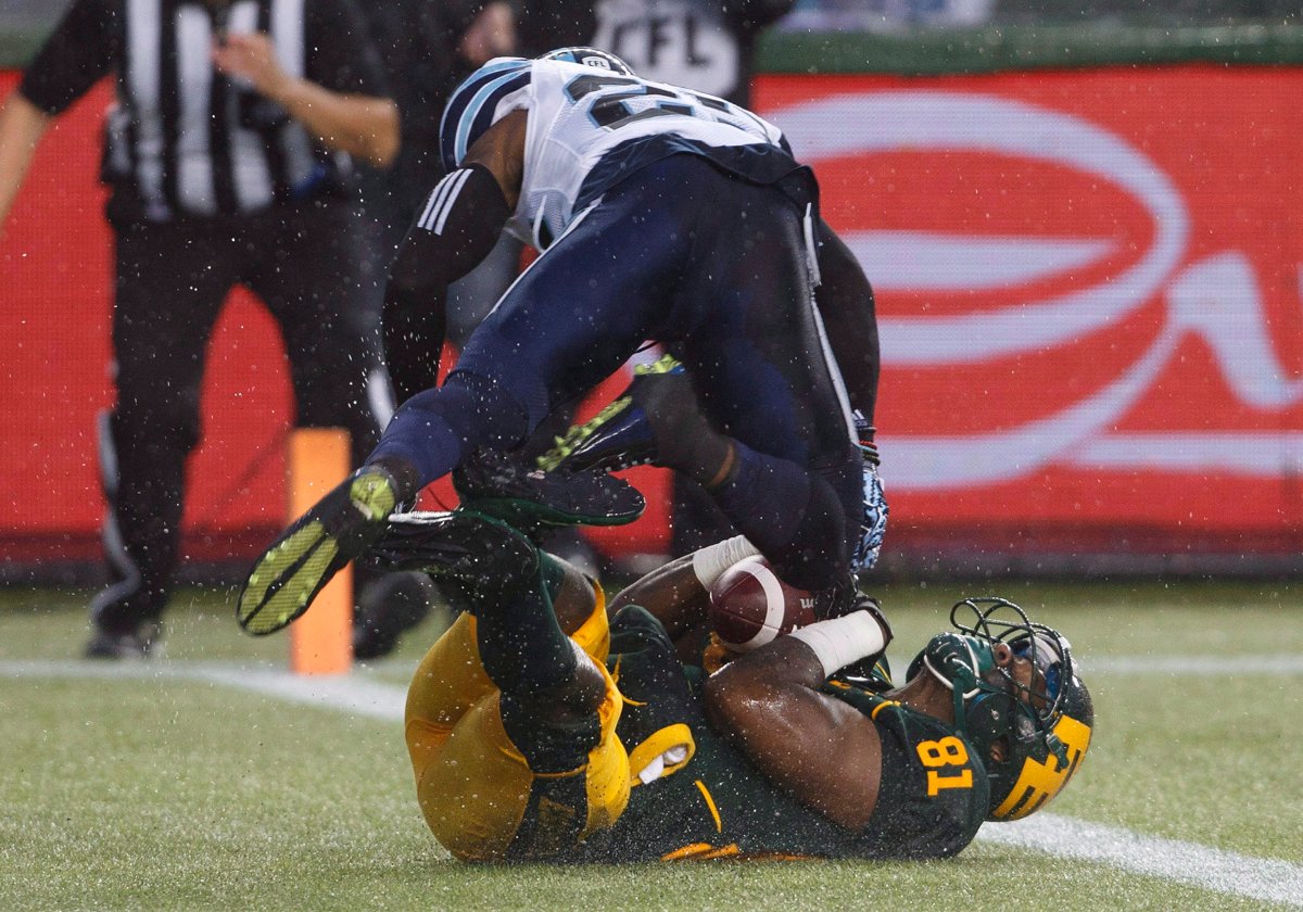 Toronto Argonauts Ronnie Yell (25) tries to stop Edmonton Eskimos D'haquille Williams (81) as he scores a touchdown during second half CFL action in Edmonton, Alta., on Friday July 13, 2018. 