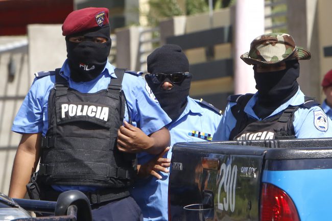 Masked police block a street as people protest demanding the release of students who had taken refuge at the Jesus of Divine Mercy church amid a barrage of armed attacks, around the National Autonomous University of Nicaragua (UNAN) in Managua, Nicaragua, Saturday, July 14, 2018. 


