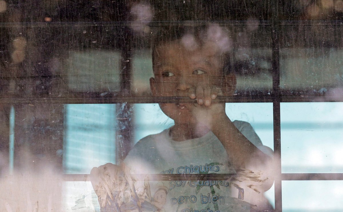 In this June 23, 2018, file photo, an immigrant child looks out from a U.S. Border Patrol bus leaving as protesters block the street outside the U.S. Border Patrol Central Processing Center in McAllen, Texas. 