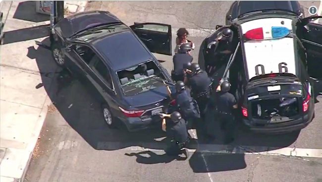 In this image from video provided by KNBC-TV, Los Angeles Police officers remove a passenger from a car that crashed after a pursuit with the driver who ran into a nearby Trader Joe’s supermarket in the Silver Lake district of Los Angeles Saturday, July 21, 2018.