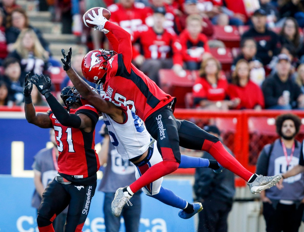 Montreal Alouettes' B.J. Cunningham, centre, reaches for the ball as Calgary Stampeders' Emanuel Davis, right, intercepts it while Tre Roberson looks on during second half CFL football action in Calgary, Saturday, July 21, 2018. 
