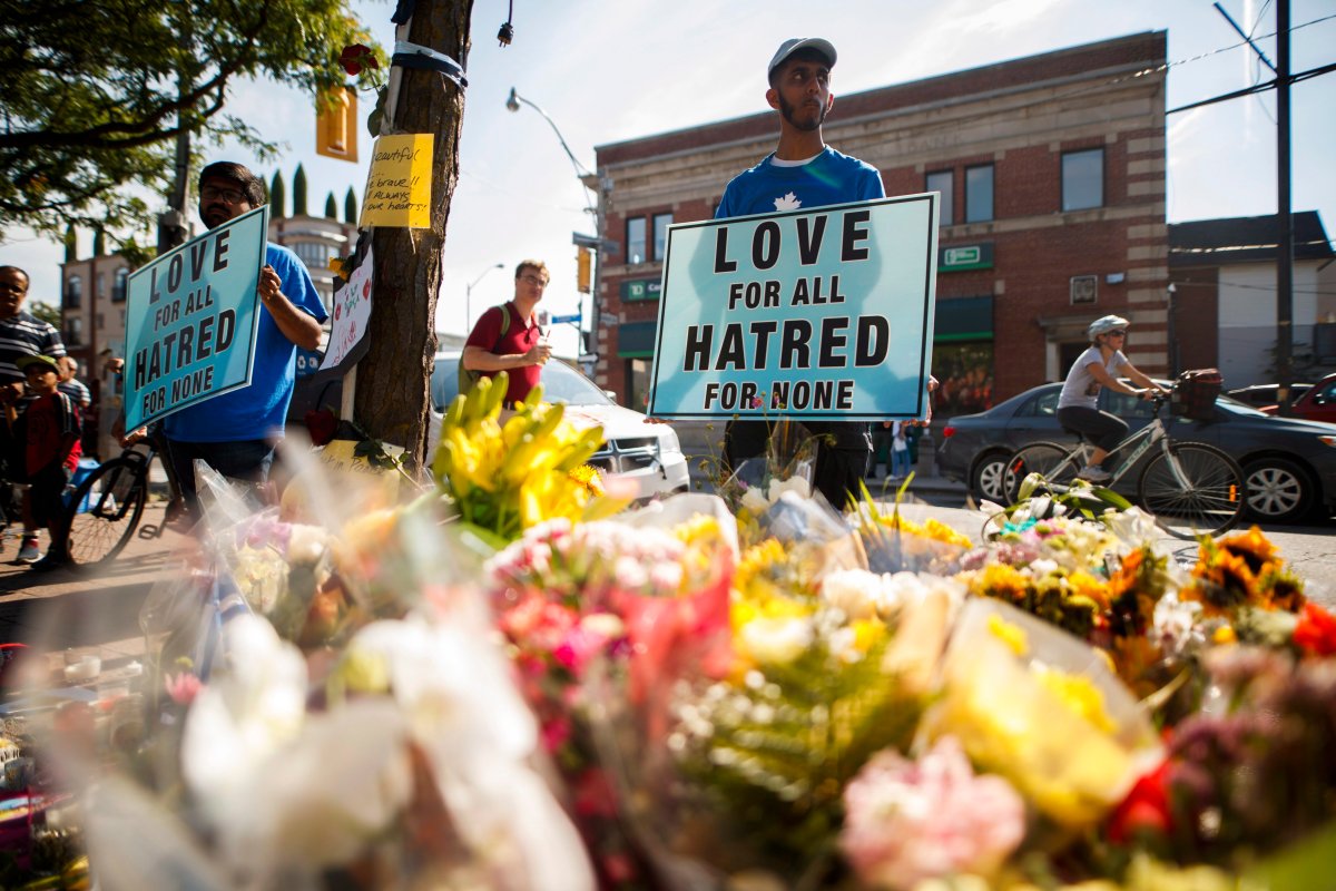 A man holds a sign reading "Love for All Hatred of None" at a memorial remembering the victims of a shooting on Sunday evening on Danforth, Avenue in Toronto on Tuesday, July 24, 2018. 
