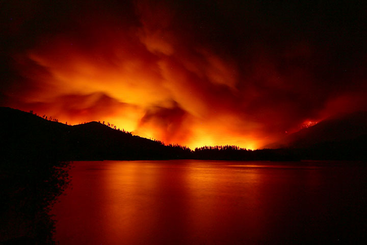 In this photo taken Wednesday, July 25, 2018, a wildfire burns near the lake in Whiskeytown, Calif.