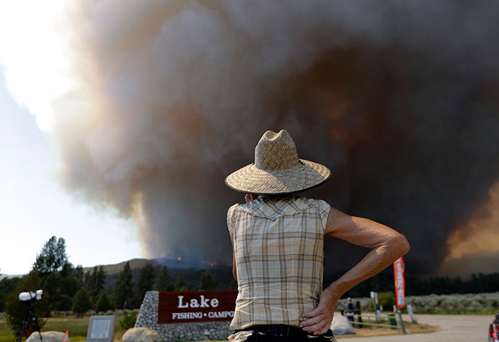 A woman watches a plume of smoke from a wildfire Thursday, July 26, 2018, in Mountain Center, Calif.