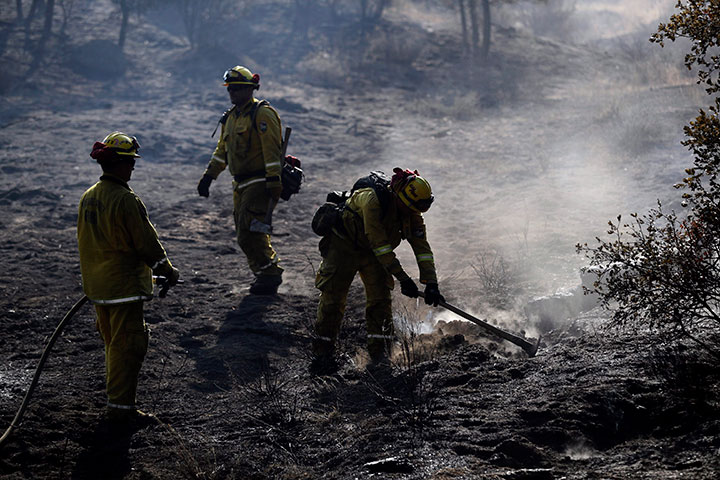 Firefighters hose down hot spots along Highway 243 on Thursday, July 26, 2018, near Idyllwild, Calif.