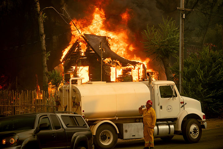 A water tender operator drinks a beverage after trying to save a home burning in Shasta, Calif., on Thursday, July 26, 2018.