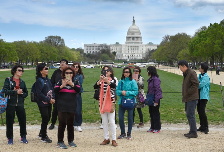 A group of tourists from China take photographs on the National Mall with the U.S. Capitol in the background in April 2018. China has issued a security advisory to Chinese nationals traveling to the United States.