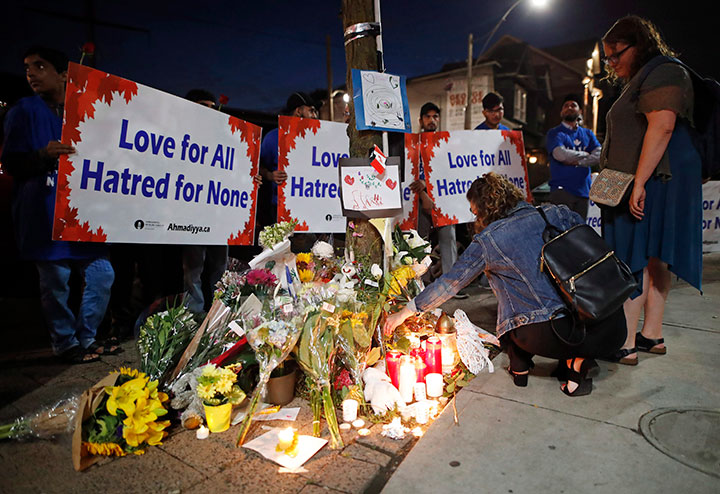 People place flowers and candles at a makeshift memorial remembering the victims of a shooting on Sunday evening on Danforth, Ave. in Toronto on Monday, July 23, 2018. 