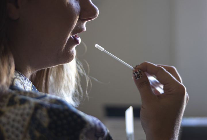 A reporter collects a saliva sample for a DNA genetic testing kit.