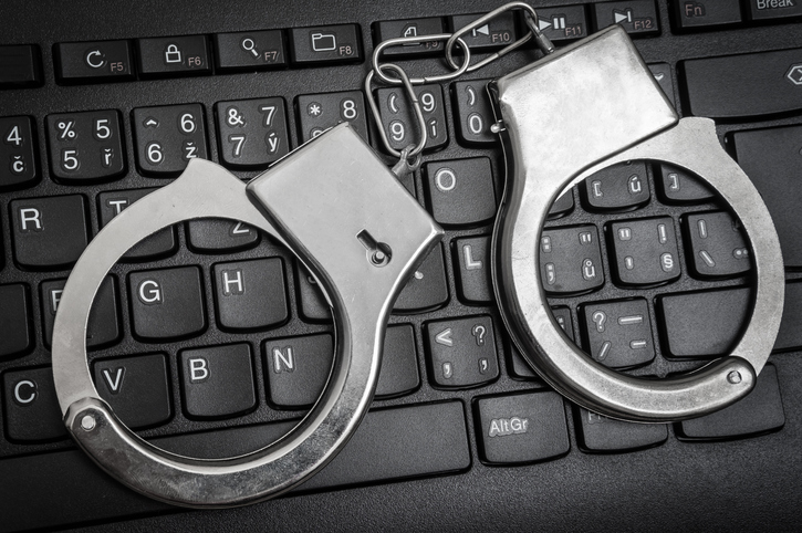 Top view of black keyboard and handcuffs - cyber crime concept.
