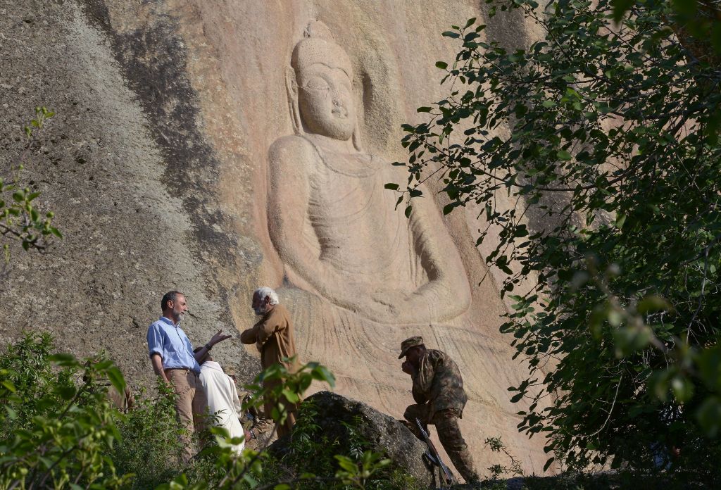 Italian archaeologist Luca Maria Olivieri speaks with Pakistani historian Parvesh Shaheen next to the seventh-century rock sculpture of a seated Buddha carved into a mountain in Jahanabad town in the northwestern Swat Valley of Pakistan, April 26, 2018.


