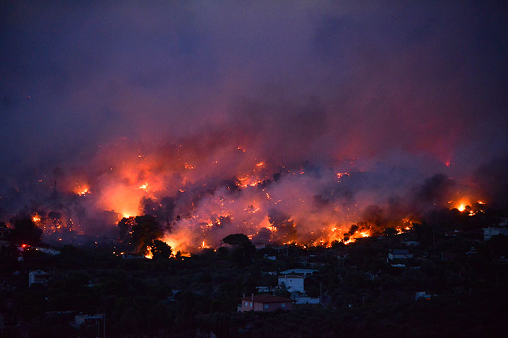 Flames rise as a wildfire burns in the town of Rafina, near Athens, on July 23, 2018.