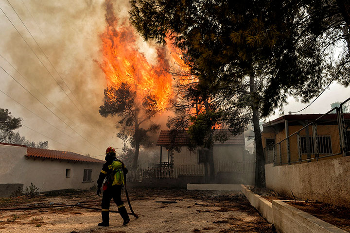 A firefighter tries to extinguish hotspots during a wildfire in Kineta, near Athens, on July 23, 2018.