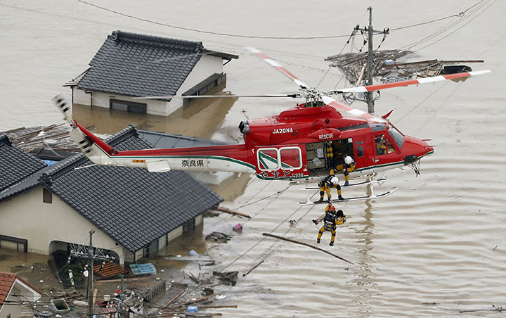 An aerial view shows a local resident being rescued from a submerged house by rescue workers using helicopter at a flooded area in Kurashiki, southern Japan, in this photo taken by Kyodo July 7, 2018.