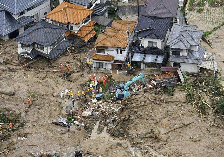 Rescue workers are seen next to houses damaged by a landslide following heavy rain in Hiroshima, western Japan, in this photo taken by Kyodo July 7, 2018.