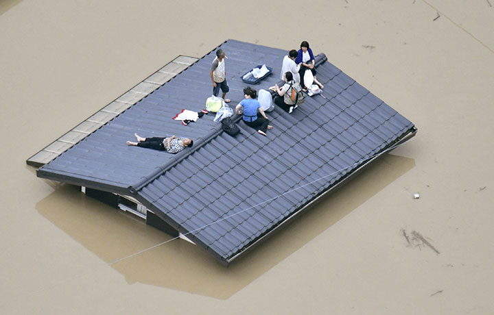 An aerial view shows local residents seen on the roof of submerged house at a flooded area as they wait for a rescue in Kurashiki, southern Japan, in this photo taken by Kyodo July 7, 2018.
