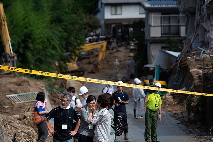 People react as they look out at a damaged street in a flood-hit area in Kumano, Hiroshima prefecture on July 9, 2018.