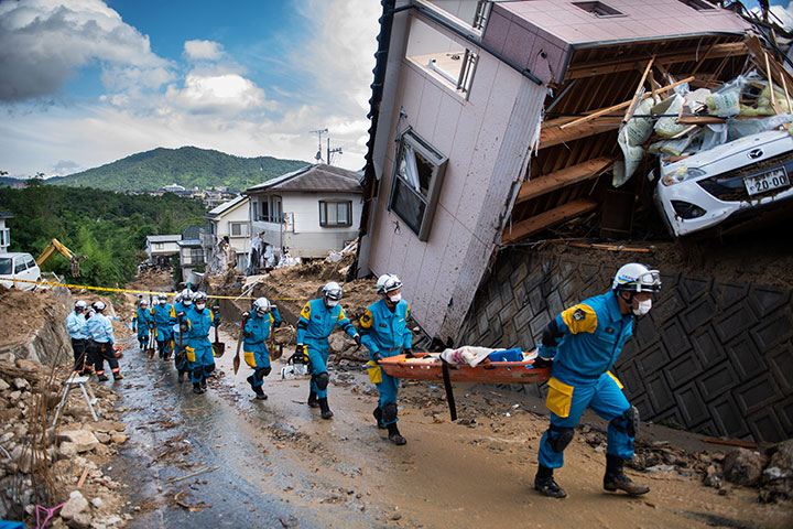 Police arrive to clear debris scattered on a street in a flood hit area in Kumano, Hiroshima prefecture on July 9, 2018.