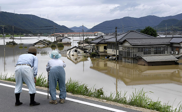 An elderly couple looks at a flooded area after heavy rain in Kurashiki, Okayama Prefecture, Japan, in this photo taken by Kyodo July 8, 2018.