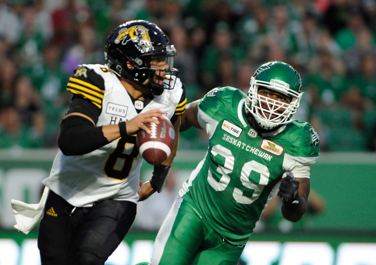 Hamilton Tiger-Cats quarterback Jeremiah Masoli, left, is chased by Saskatchewan Roughriders defensive lineman Charleston Hughes during second half CFL action at Mosaic Stadium in Regina on Thursday, July 5, 2018.