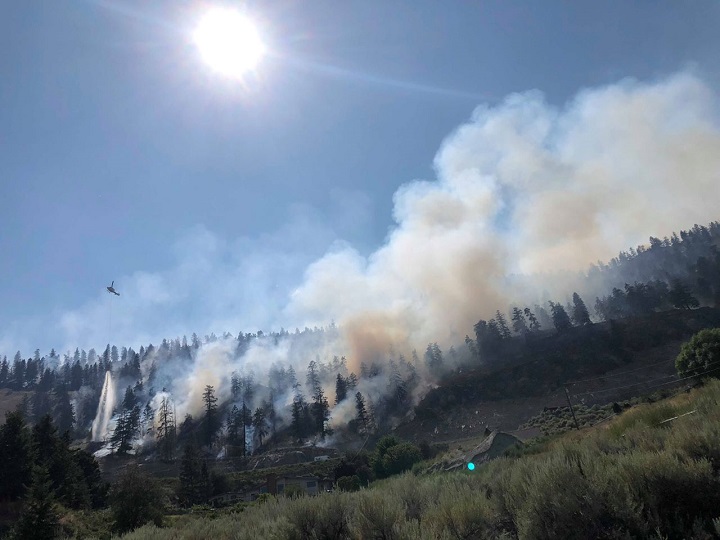 A helicopter buckets water on a fire in the Okanagan.