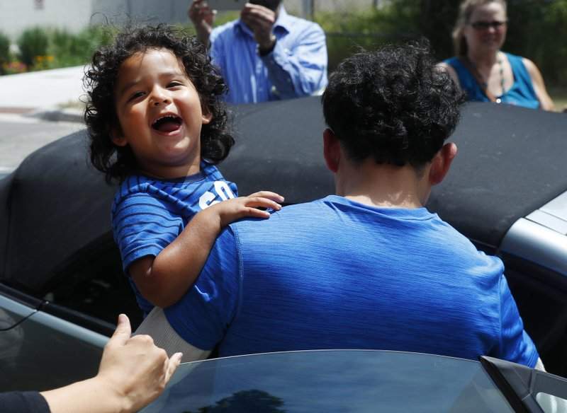 Ever Reyes Mejia, of Honduras, carries his son to a vehicle after being reunited and released by United States Immigration and Customs Enforcement in Grand Rapids, Mich., Tuesday, July 10, 2018.