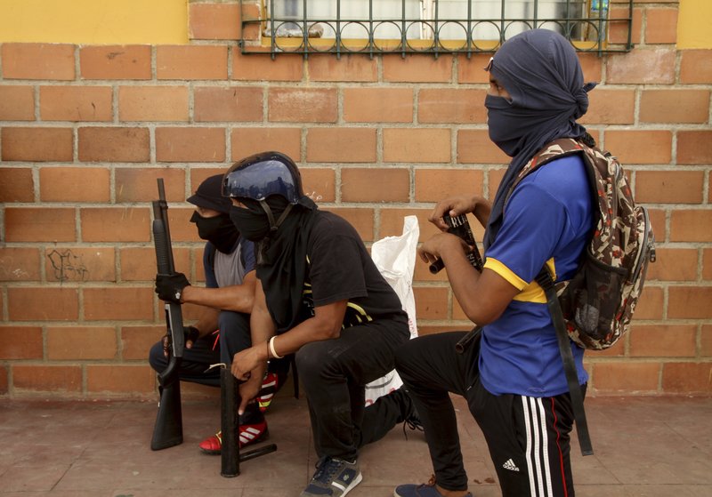 Opponents to the government of Nicaraguan President Daniel Ortega stand watch behind a barricade as the government forces enter the city in Masaya, Nicaragua, Tuesday, June 19, 2018.