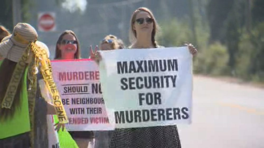 Protesters gather on the side of the road outside Mission Institution Sunday July 29 against the arrival of Walter Ramsey, who is being transferred from a maximum security prison.