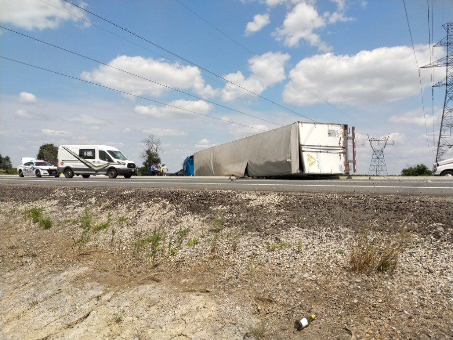 A transport truck sits rolled over on its side on Veterans Memorial Parkway, just north of Highway 401.