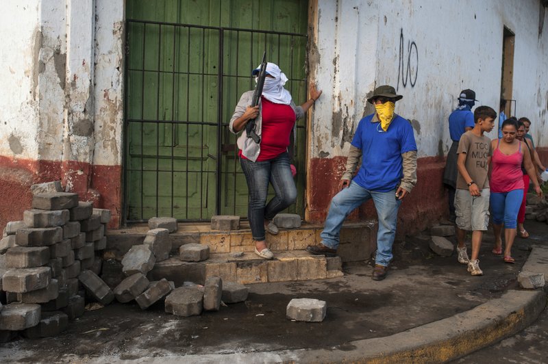 In this Tuesday, July 17, 2018, photo, Sandinista militias stand guard at a dismantled barricade after police and pro-government militias stormed the Monimbo neighbourhood of Masaya, Nicaragua.