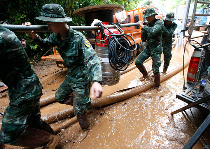 Soldiers carry a pump to help drain the rising flood water in a cave where 12 boys and their soccer coach have been missing in Mae Sai, Chiang Rai province, northern Thailand, Friday, June 29, 2018.
