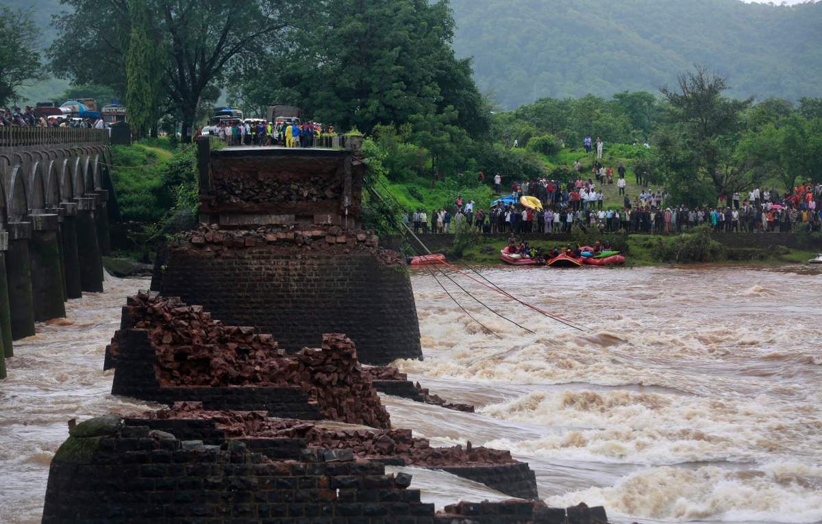 People watch the search operation in the flooded River Savitri after an old bridge collapsed in Mahad, western Maharashtra state, India, Wednesday, Aug. 3, 2016.