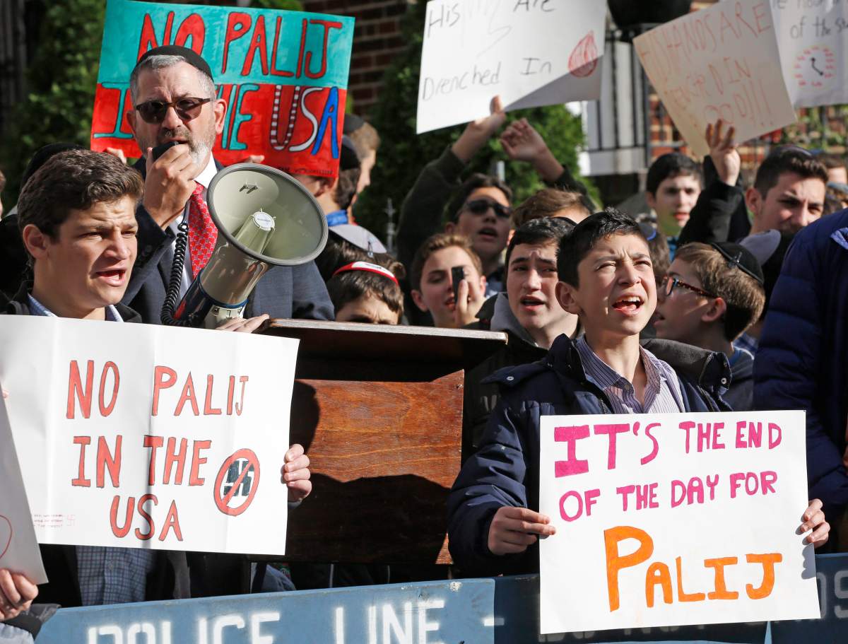 Rabbi Zev Friedman, dean of the Rambam Mesivta, Orthodox Jewish high school, second from left, speaks as his students protest across the street from the home of a former Nazi prison camp guard whose citizenship has been revoked but hasn’t been deported, Thursday, Nov. 9, 2017, in the Jackson Heights neighborhood of New York.