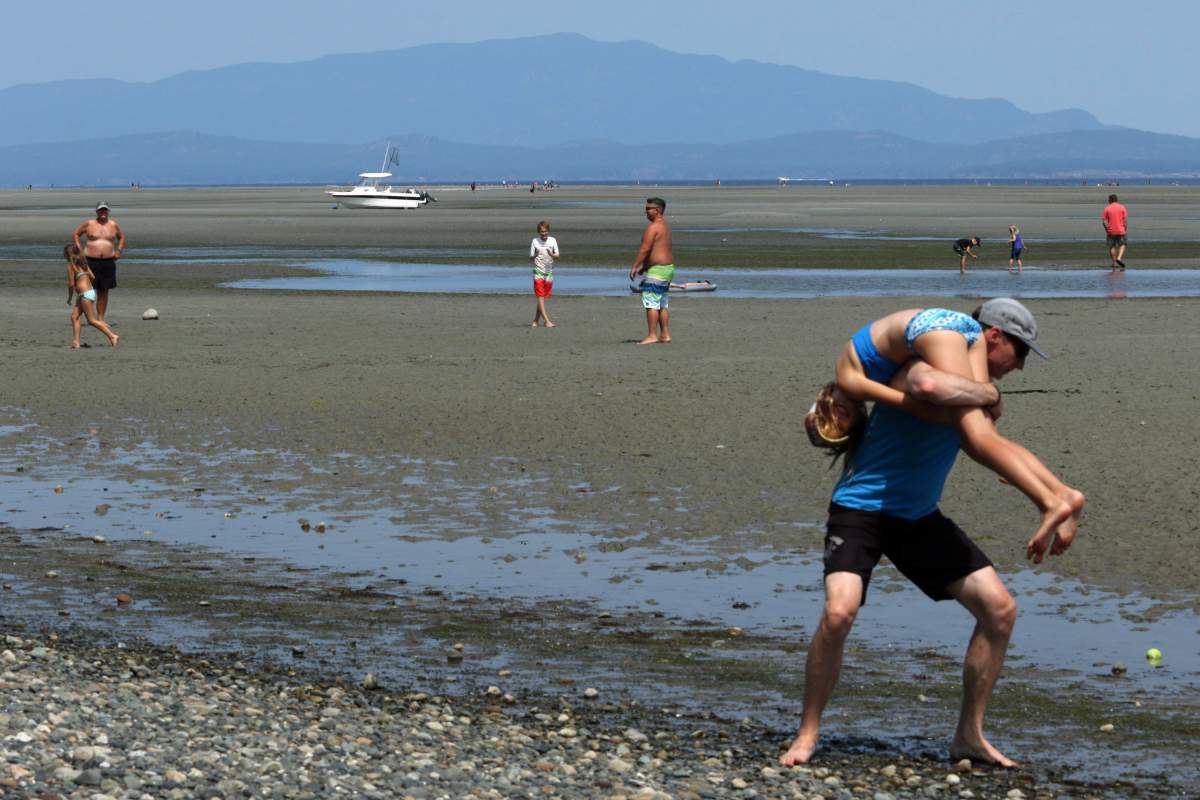 People enjoy the heat wave across Vancouver Island during a low tide at Rathtrevor Beach Provincial Park in Parksville, B.C., on Friday, July 27, 2018. 