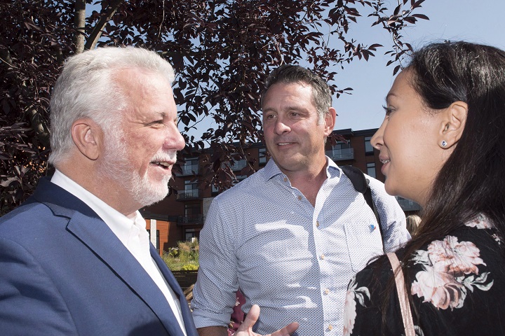Quebec Liberal Leader Philippe Couillard, left, chats with Saint-Laurent candidate Marwah Rizqy, right, while Marquette candidate Enrico Ciccone, centre, looks on before at a meeting of candidates in preparation for the general election, Monday, August 20, 2018 in Scott Que. 
