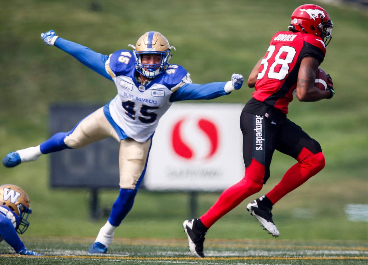 Winnipeg Blue Bombers' Jovan Santos-Knox, left, dives for Calgary Stampeders' Kamar Jorden during first quarter CFL football action in Calgary, Saturday, Aug. 25, 2018. THE CANADIAN PRESS/Jeff McIntosh.