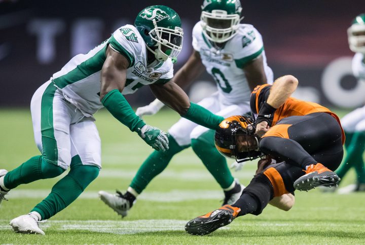 B.C. Lions' quarterback Travis Lulay, right, tumbles ahead to avoid a tackle from Saskatchewan Roughriders' Samuel Eguavoen, left, during the second half of a CFL football game in Vancouver, on Saturday August 25, 2018. 